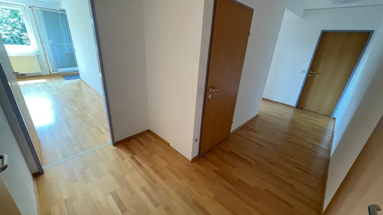 Heller Flur mit Holzfußboden und Zugang zu verschiedenen Zimmern, bietet einen ersten Einblick in die Wohnung.