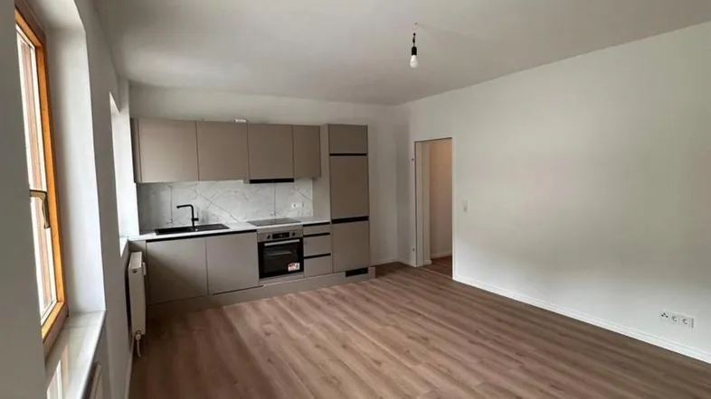 Moderne Einbauküche in einem hellen Raum mit neuem Laminatboden und Fenster für Tageslicht.