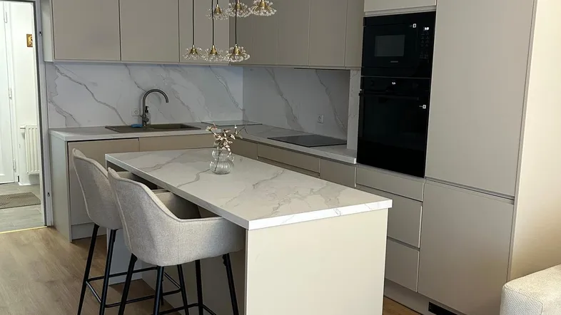 Moderne Küche mit Kücheninsel, integrierten Geräten und hellem Marmor-Look-Arbeitsplatten.