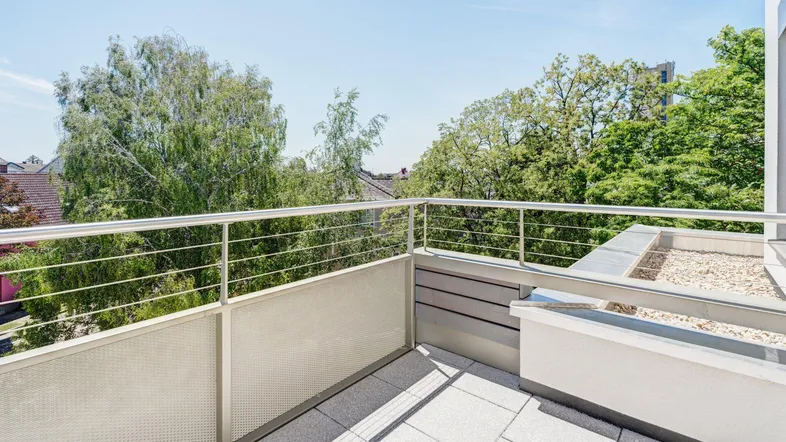 Heller Balkon mit Fliesenboden und moderner Metallbrüstung, bietet einen grünen Ausblick.
