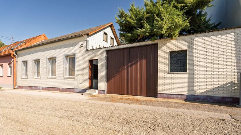 Fassade eines Einfamilienhauses mit weißem Ziegelmauerwerk und großem braunen Garagentor.
