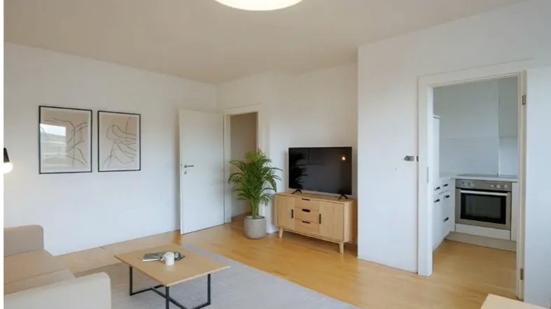 Helles Wohnzimmer mit Parkettboden, moderner Einrichtung und Blick in die angrenzende Küche.