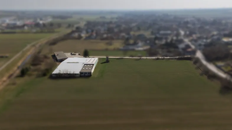 Luftaufnahme eines Industriegebäudes umgeben von Feldern und ländlicher Umgebung mit Weitblick.