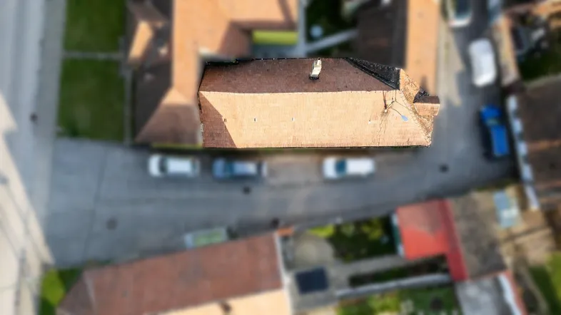 Luftaufnahme eines Wohnhauses mit Ziegeldach und umliegenden Gebäuden in einer Siedlung.