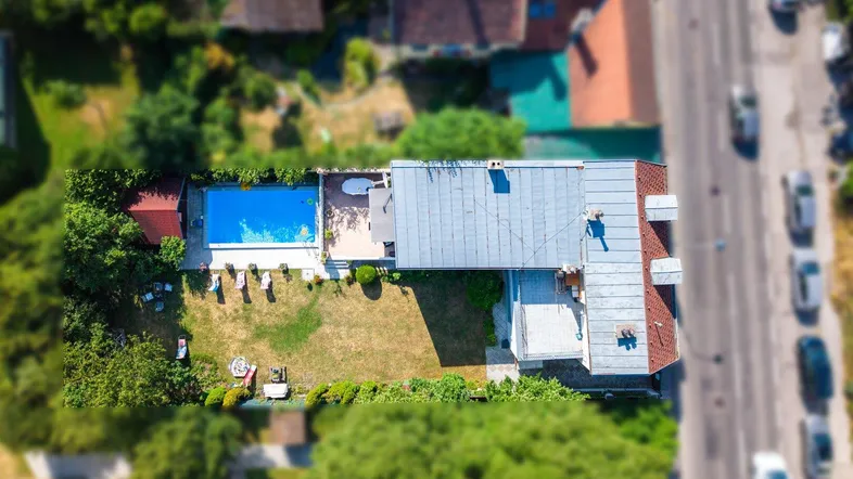 Luftaufnahme des Anwesens mit Pool, Garten und angrenzender Straße.