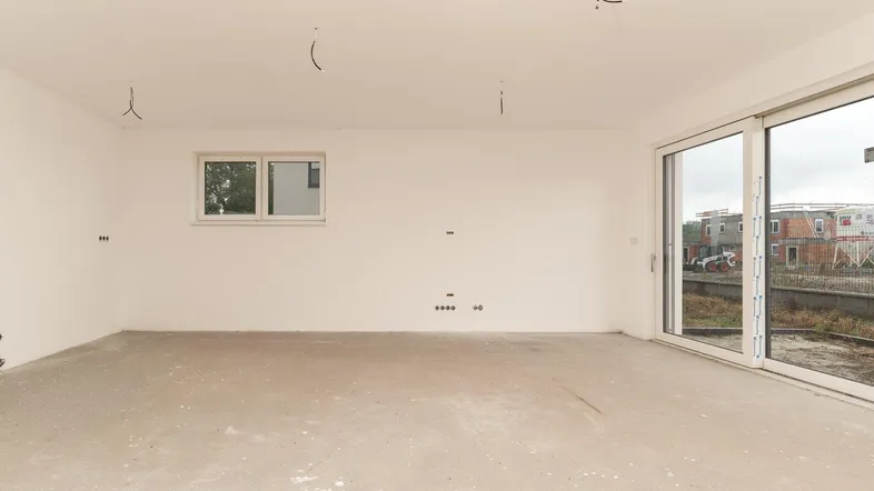 Unfertiger Wohnbereich mit großen Schiebetüren und Blick auf die Baustelle.