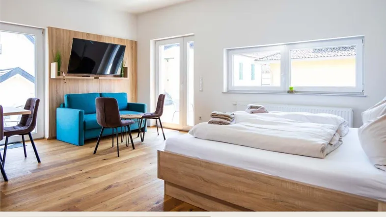 Helles Schlafzimmer mit Holzboden, einem Doppelbett und einem kleinen Sitzbereich mit Fernseher.