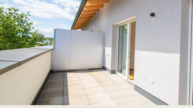 Geräumige Terrasse mit Fliesenboden und Blick auf die Umgebung, ideal für entspannte Stunden im Freien.