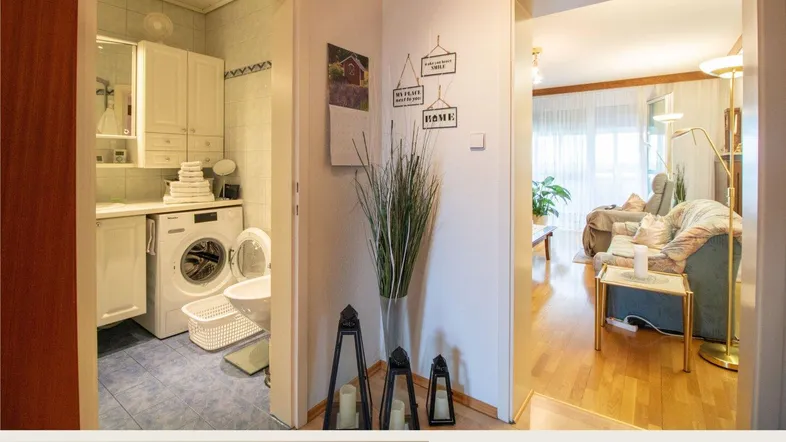 Heller Eingangsbereich mit Blick in das Badezimmer und das Wohnzimmer, ausgestattet mit Holzfußboden.