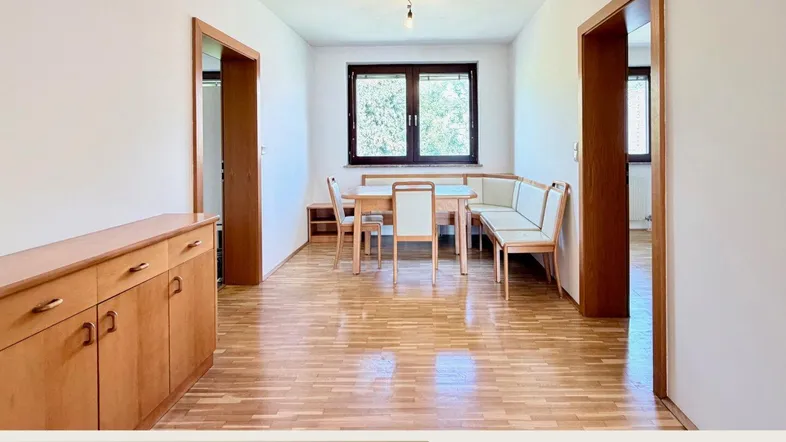 Heller Essbereich mit Parkettboden, Holzmöbeln und einem Fenster mit Blick ins Grüne.