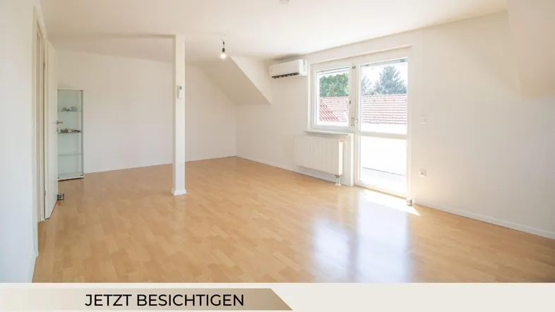 Helles Wohnzimmer mit Holzboden, Dachschräge und Zugang zum Balkon.