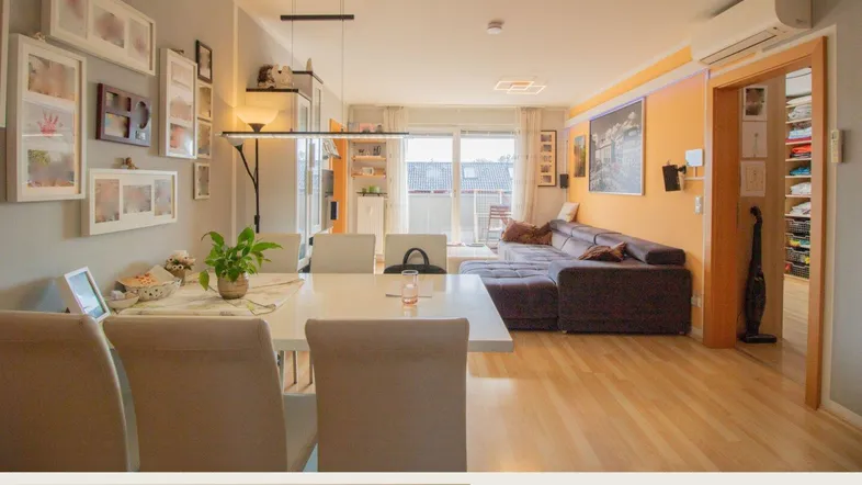 Heller offener Wohn- und Essbereich mit modernem Esstisch, bequemer Couch und Zugang zum Balkon.
