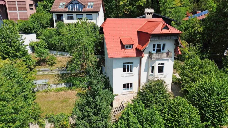 Luftaufnahme eines freistehenden Hauses mit rotem Ziegeldach und umgebender grüner Vegetation.