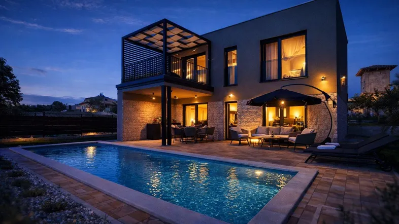 Moderne Villa bei Nacht mit beleuchtetem Pool, großer Terrasse und Balkon mit Pergola.