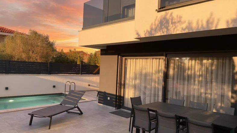 Große Terrasse mit Esstisch, Sonnenliege und privatem Pool bei Sonnenuntergang.