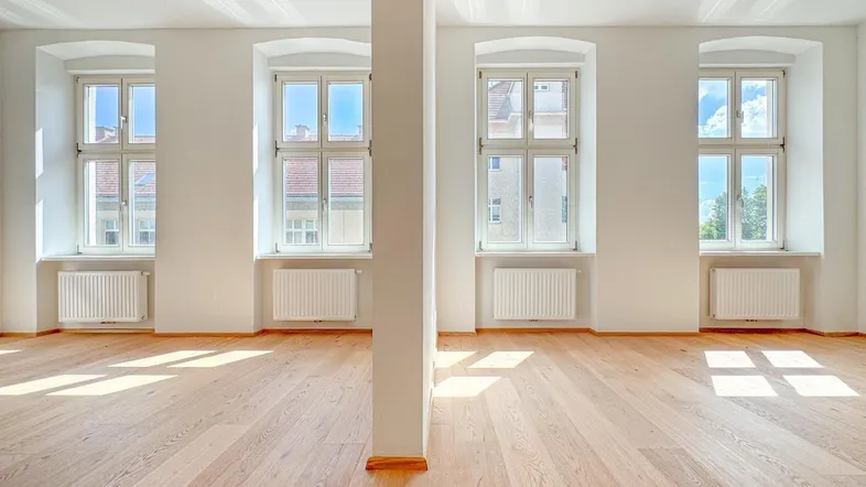 Geräumiger, leerer Raum mit hohen Decken, Holzboden und großen Fenstern, lichtdurchflutet.