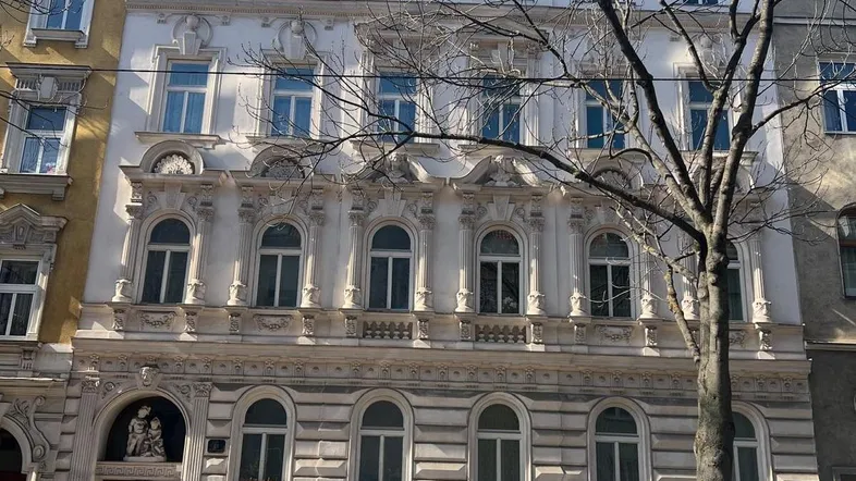 Historische Fassade eines Wiener Wohnhauses mit reich verzierten Fenstern und Balkonen.