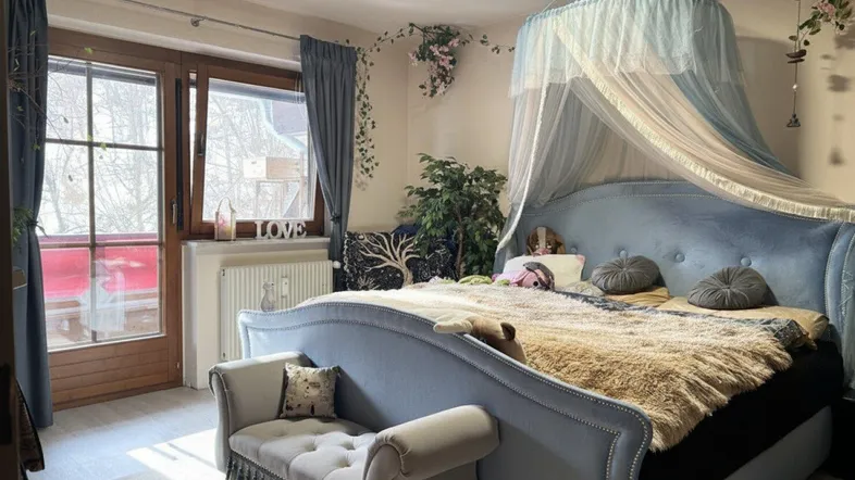Helles Schlafzimmer mit großem blauen Himmelbett, Baldachin und direktem Zugang zum Balkon.