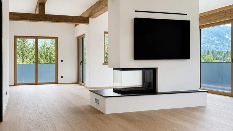 Helles Wohnzimmer mit Holzbalken, modernem Kamin und Zugang zu einem Balkon mit Bergblick.