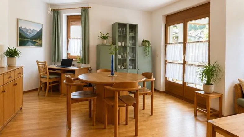 Heller Wohn- und Essbereich mit Holzboden, Esstisch und einem Arbeitsplatz am Fenster.