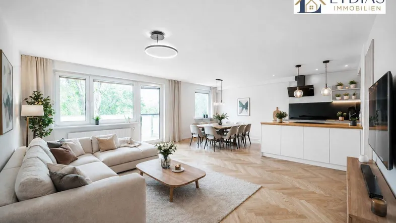 Heller, offener Wohn- und Essbereich mit moderner Küche, Parkettboden und Zugang zum Balkon.