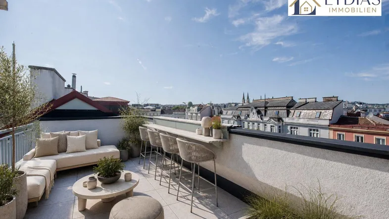 Geräumige Dachterrasse mit bequemen Lounge-Möbeln und einem Bartresen unter blauem Himmel.