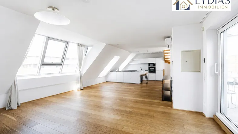 Geräumiger, heller Wohnbereich mit Holzboden, Dachschrägen und integrierter moderner Küche.
