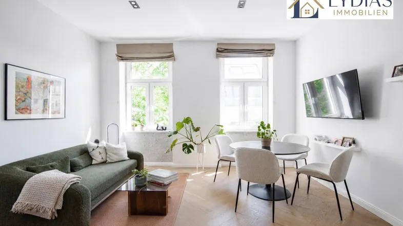 Helles Wohn- und Esszimmer mit modernem Sofa, Esstisch und Parkettboden.