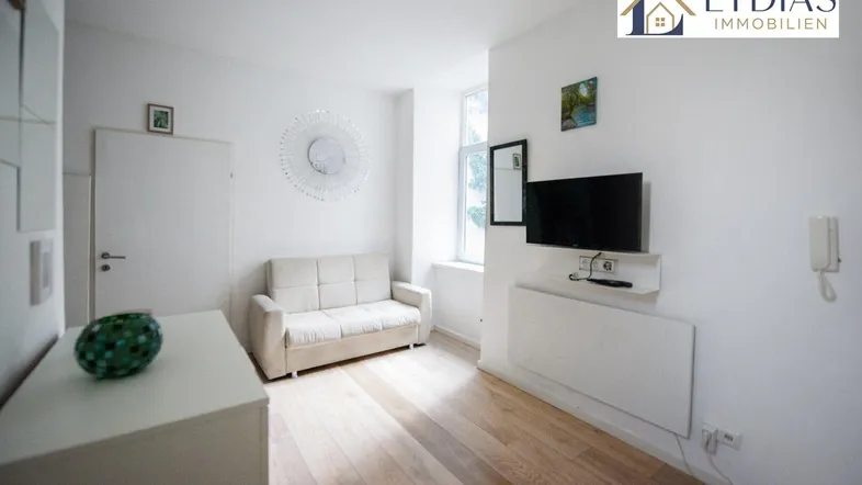 Helles Wohnzimmer mit Parkettboden, Sofa und Fernseher, ideal für entspannte Stunden.