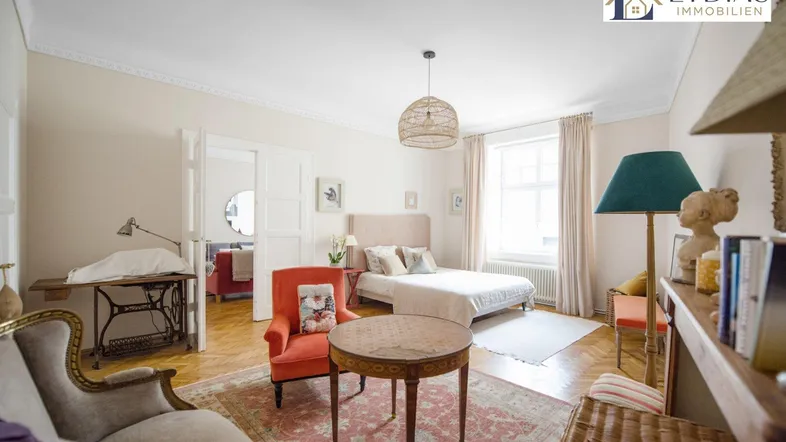 Helles Schlafzimmer mit Parkettboden, Stuckdecken und einem gemütlichen Sitzbereich in Altbauwohnung.