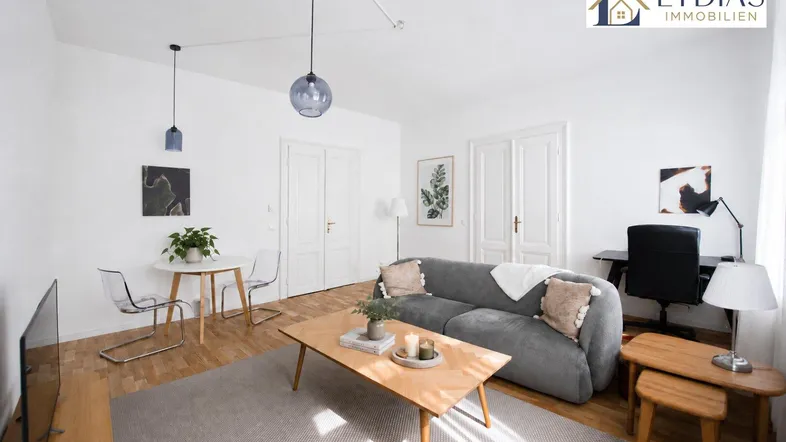 Helles Wohnzimmer mit modernem Sofa, Holzboden und einem kleinen Essbereich.