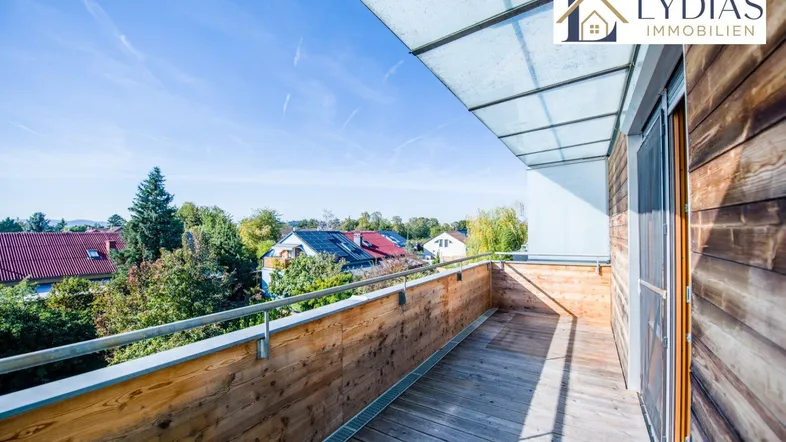 Geräumiger Balkon mit Holzboden und Überdachung, bietet einen weiten Blick über die Umgebung.