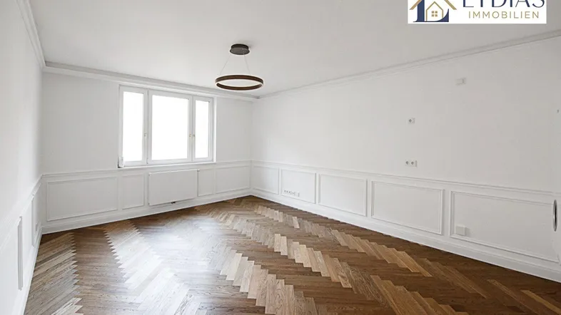 Helles, leeres Zimmer mit Fischgrätparkett und dekorativen Wandleisten, bereit zur individuellen Gestaltung.