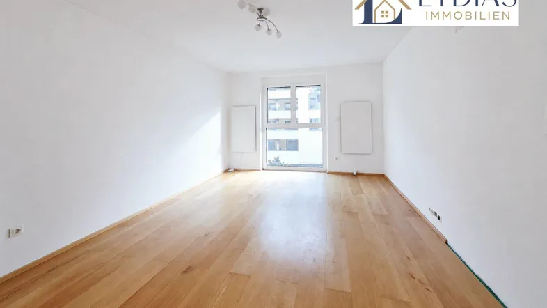 Helles, leeres Wohnzimmer mit Parkettboden und großen Fenstern, bereit zur individuellen Gestaltung.