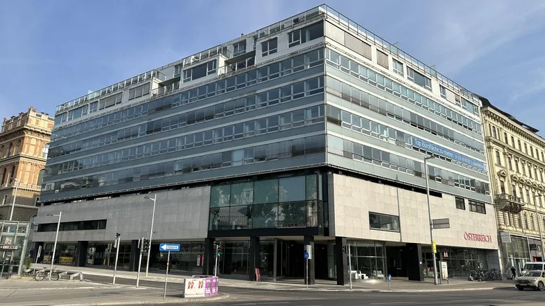 Modernes Bürogebäude mit Glasfassade und mehreren Etagen an einer belebten Straße gelegen.