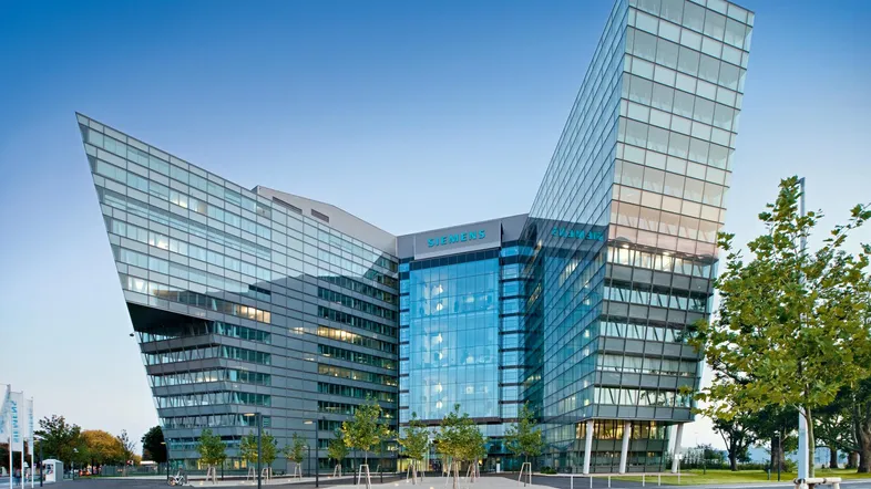 Modernes Bürogebäude mit markanter Glasfassade und einzigartiger Architektur, umgeben von Grünflächen.