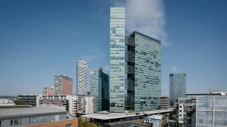 Moderne Hochhäuser prägen die Skyline einer Stadt unter blauem Himmel mit leichter Bewölkung.