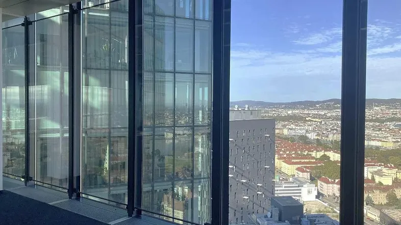 Moderner Büroraum mit großen Glasfenstern und weitem Blick über die Stadtlandschaft.