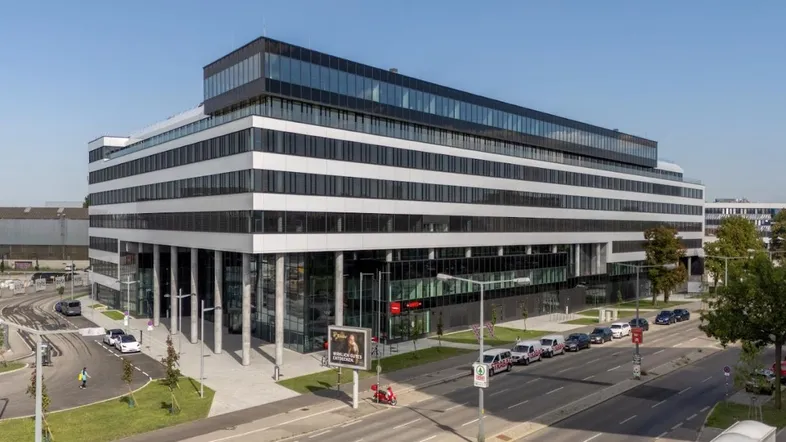Modernes Bürogebäude mit markanter Fassade und großen Glasflächen an einer belebten Straße.