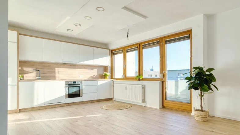 Helle, moderne Küche mit weißen Schränken, Holzakzenten und Zugang zum Balkon.