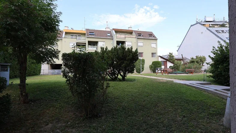 Gemeinschaftlicher Gartenbereich mit Rasenfläche und Spielplatz im Innenhof der Wohnanlage.