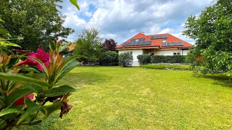 Großzügiger Gartenbereich mit gepflegtem Rasen und Blick auf das Wohnhaus mit Solaranlage.