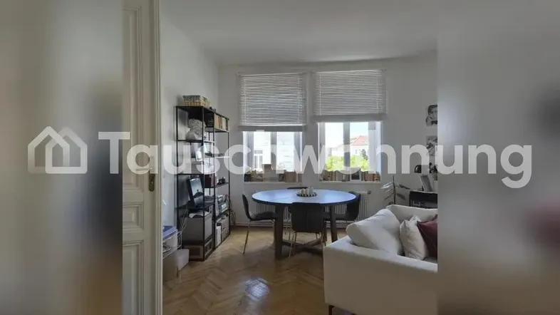 Heller Wohn- und Essbereich mit Fischgrätparkett, runden Esstisch und bequemen Sofa.