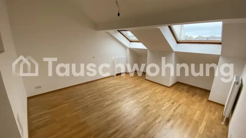 Heller Raum mit Dachschrägen, Holzboden und zwei Dachfenstern, ideal für flexible Nutzung.