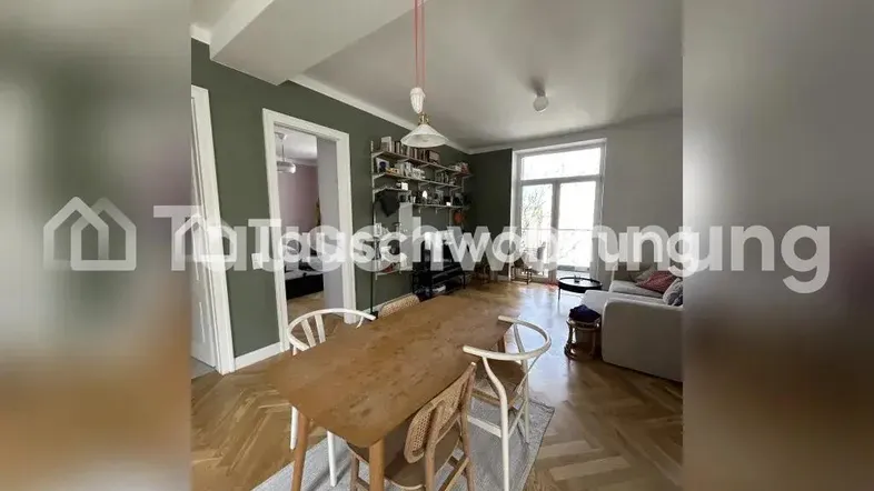Helles Wohn- und Esszimmer mit Fischgrätparkett, Holztisch und gemütlichem Sofa.