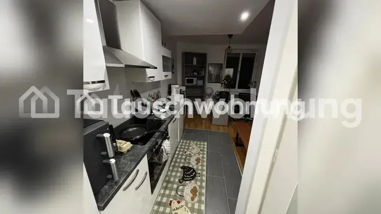 Moderne Küche mit weißen Schränken, dunkler Arbeitsplatte und Blick in den Wohnbereich.
