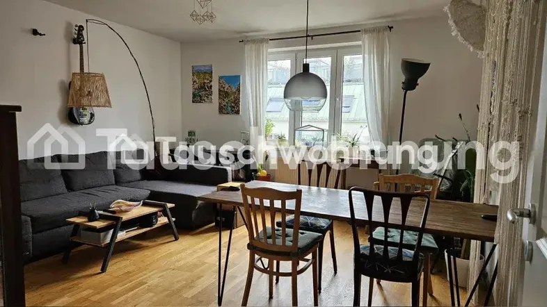 Helles Wohnzimmer mit Holzboden, Sofa und Esstisch, offen zum Essbereich.