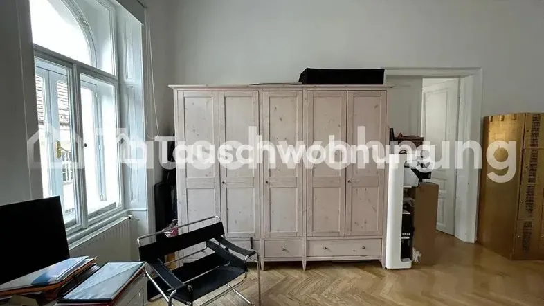 Geräumiger Wohnbereich mit Fischgrätparkett, großem Kleiderschrank und Arbeitsplatz am Fenster.