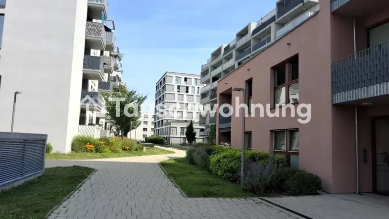 Moderne Wohngebäude mit gepflasterten Wegen und begrünten Außenbereichen unter blauem Himmel.