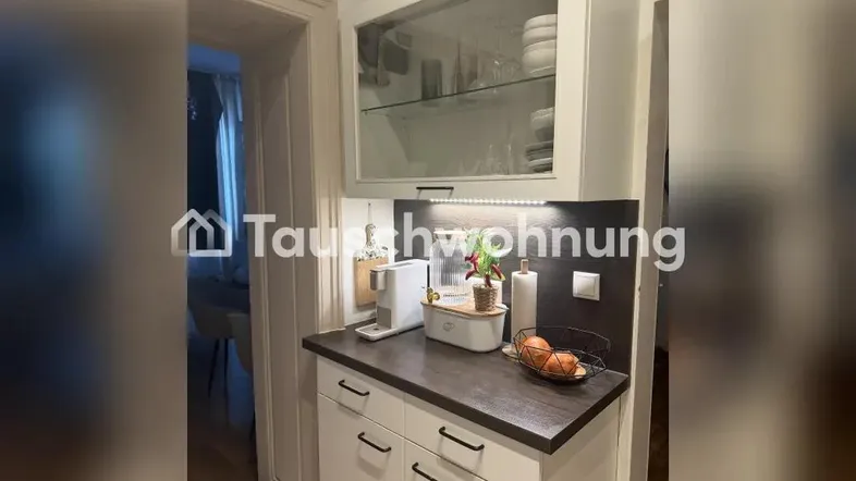 Kleine Küchenzeile mit Oberschrank, Kaffeemaschine und Blick in den angrenzenden Raum.